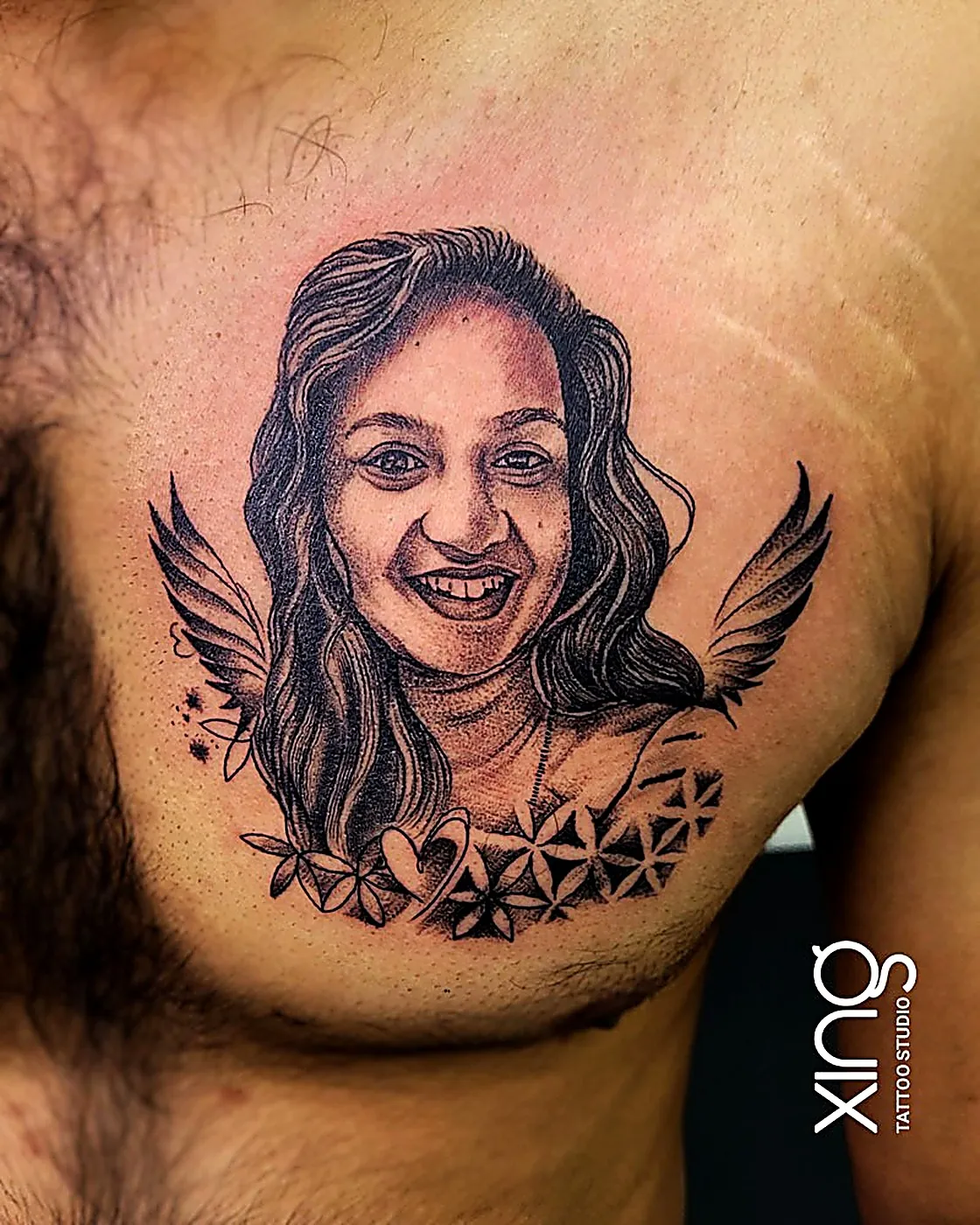 Portrait tattoo of a smiling woman with wings and florals on chest