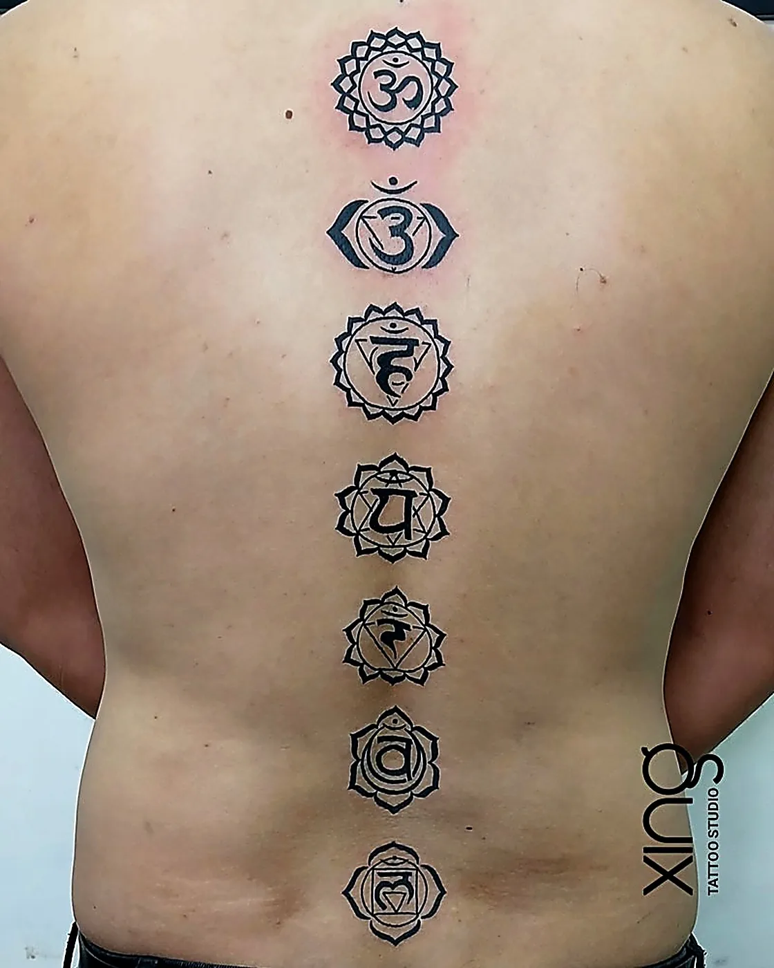 Chakra symbols geometric tattoo along the spine