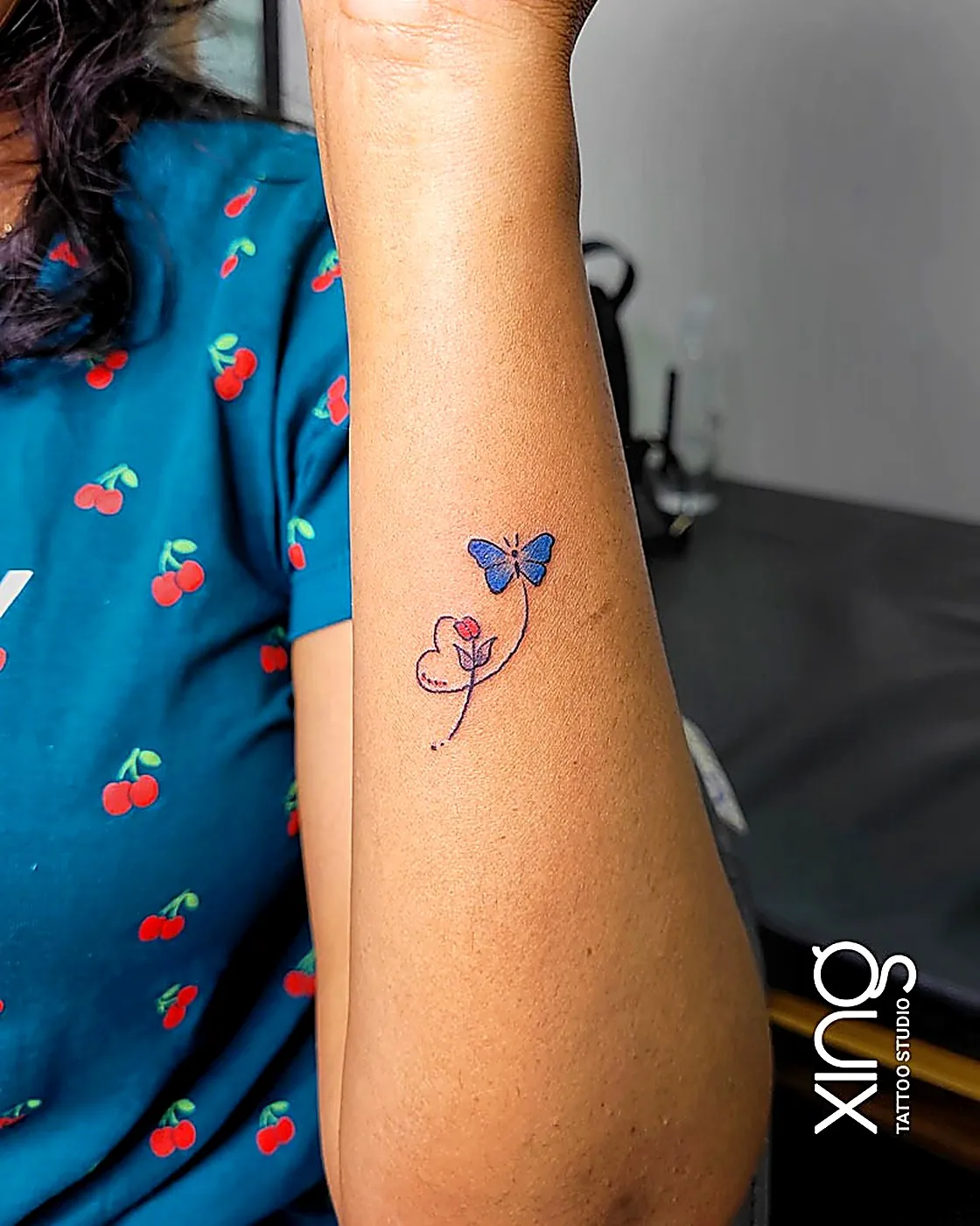 Fine-line butterfly and heart tattoo on arm