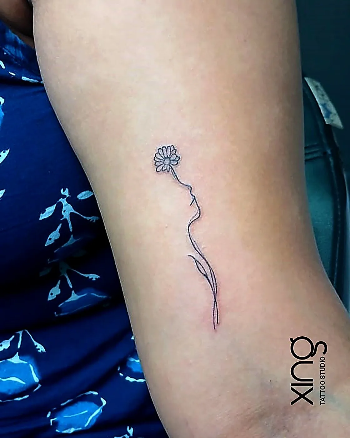 Single-line daisy flower tattoo on forearm