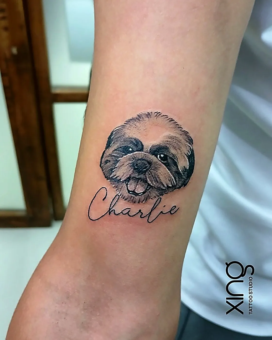 Pet portrait tattoo of a dog named Charlie on forearm