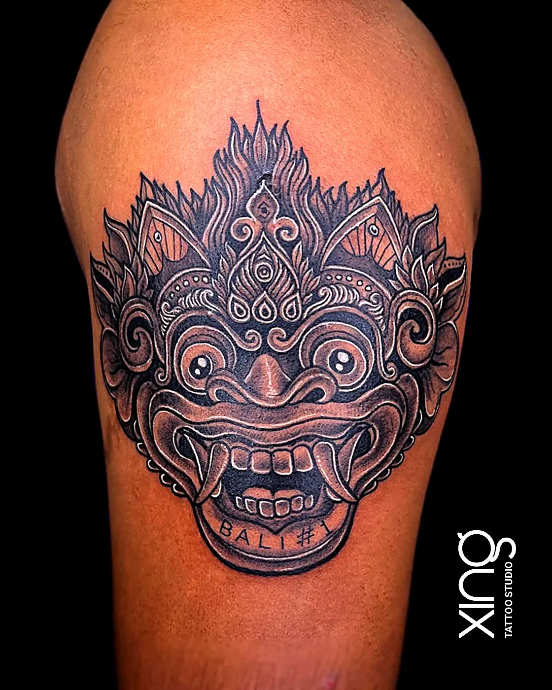 Bold mask tattoo with shading on upper arm