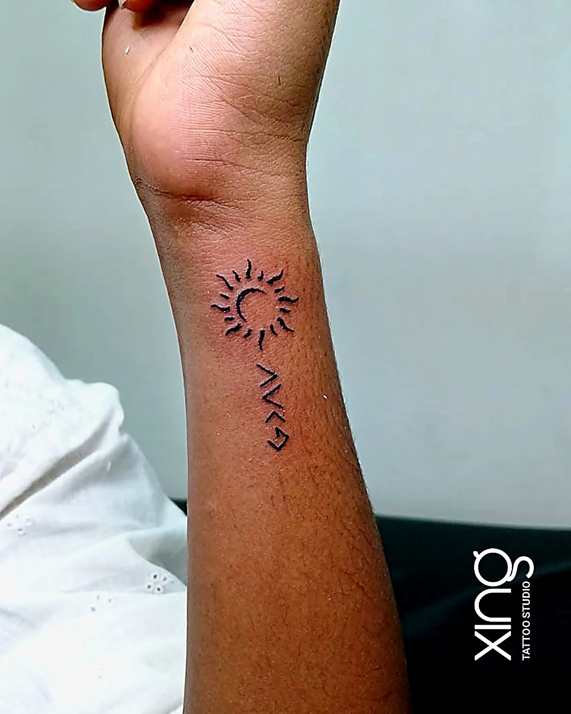 Minimalist sun and rune symbols tattoo on wrist
