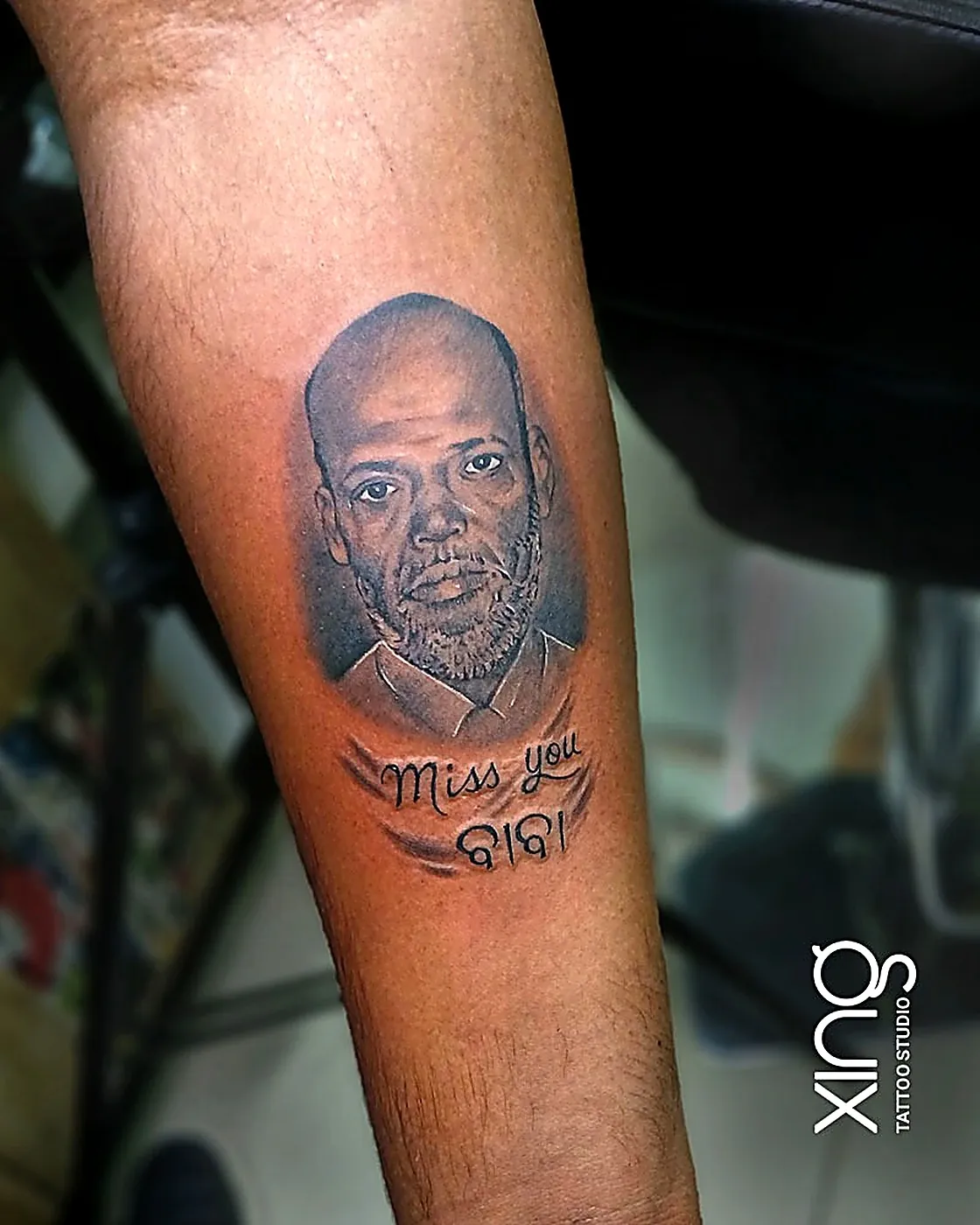 Memorial portrait tattoo tribute reading Miss You on forearm