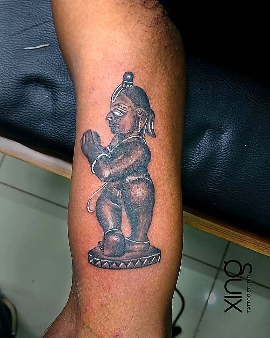 Realistic statue-style Hanuman idol tattoo on forearm