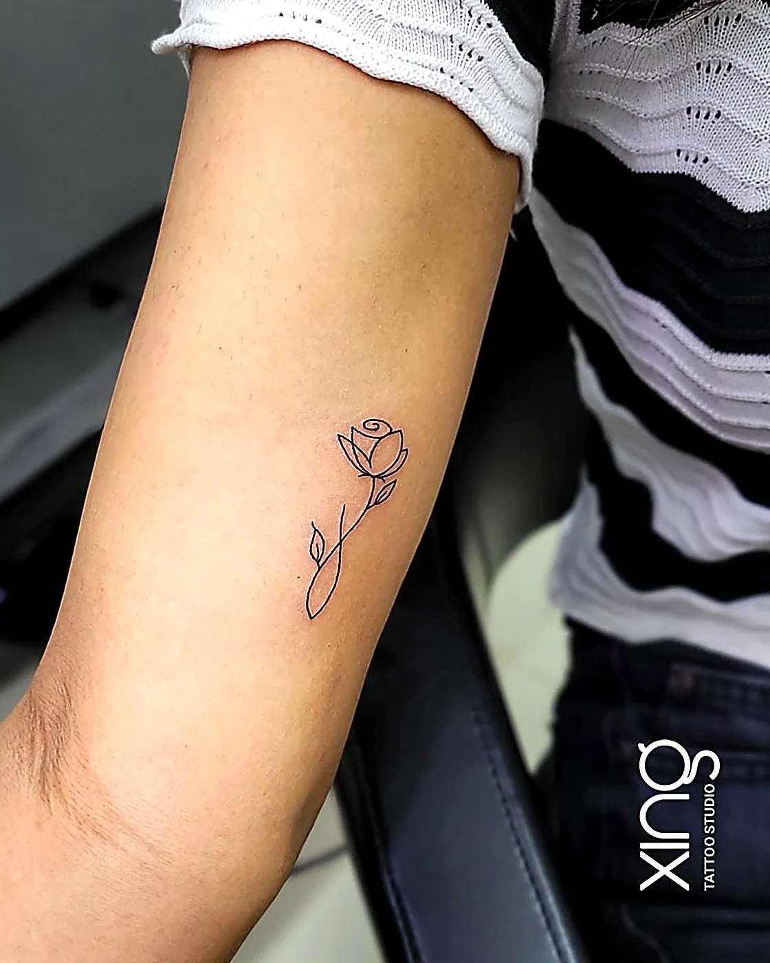 Single-line rose tattoo on arm